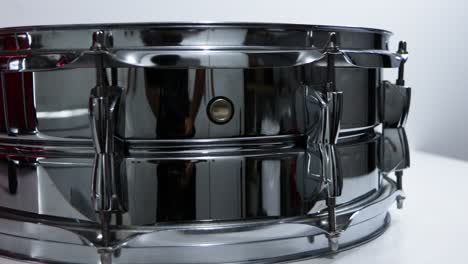 Steel-snare-drum-close-up-panning-against-white-background