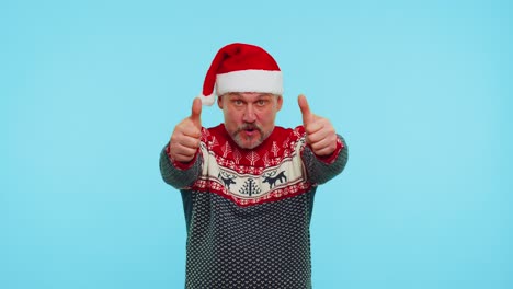 funny man wears red new year sweater with deers raises thumbs up agrees with something good like