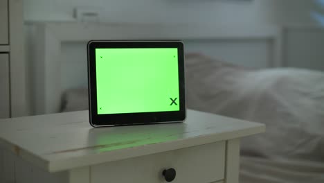 a modern digital clock with a green display, strategically placed in a room at home