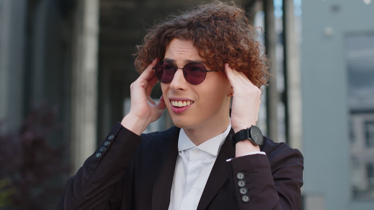 Caucasian businessman in formal suit feels a headache migraine on the street near an office building
