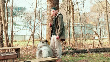 this young man commands his fluffy gray dog to sit down