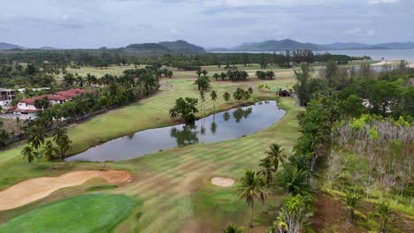 drone footage captures a lush golf course in phuket, thailand, showcasing vibrant greens, palm trees, and serene water features