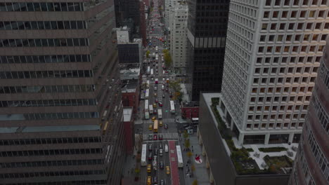 Tiro-Ascendente-Inclinado-Hacia-Abajo-De-Una-Calle-Ancha-De-Sentido-único-Rodeada-De-Altos-Y-Modernos-Edificios-De-Oficinas-O-Apartamentos.-Vehículos-Circulando-Por-Avenida.-Manhattan,-Ciudad-De-Nueva-York,-Estados-Unidos