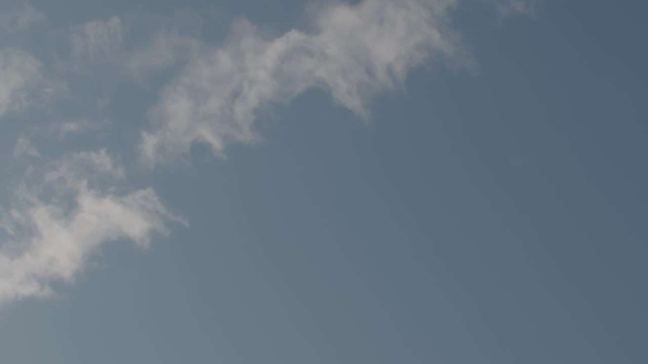 Slowmotion-totalbillede af en sveddækket basketball, der svæver i en bue gennem en skyfyldt himmel
