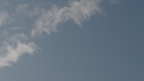 Slow-motion-wide-shot-of-a-sweat-covered-basketball-as-it-arcs-through-a-sky-with-clouds