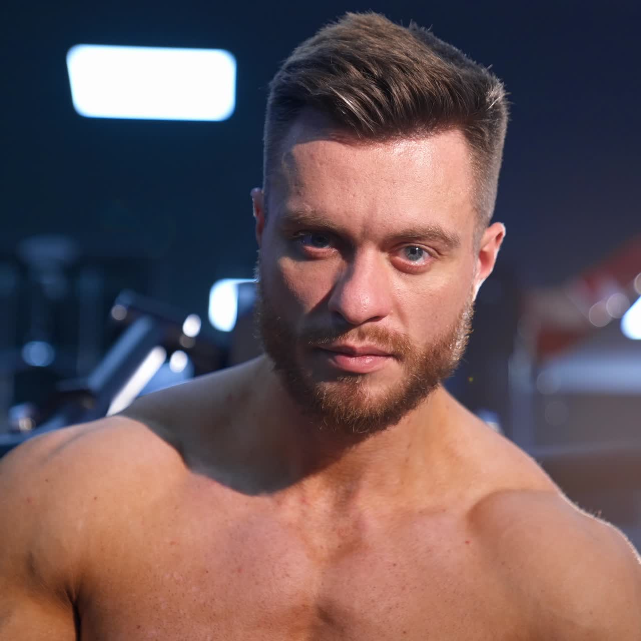 Handsome man with big muscles, posing on the camera in the gym. Slow motion