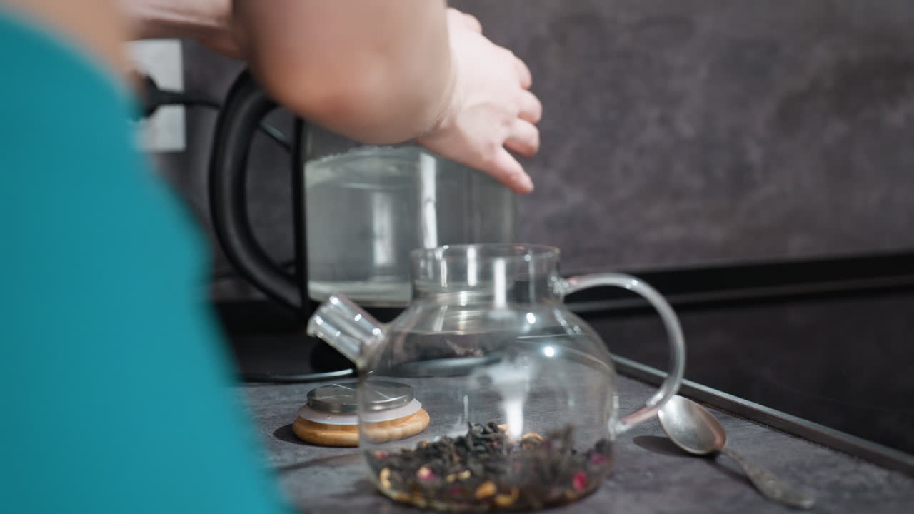 Brewery Pours Water, Casual Home Brewing With Steaming Kettle And Loose Tea Blend, Relaxed Moment Of Preparing Tea With Hot Water Pouring Into Filled Teapot In Comfortable Kitchen Environment