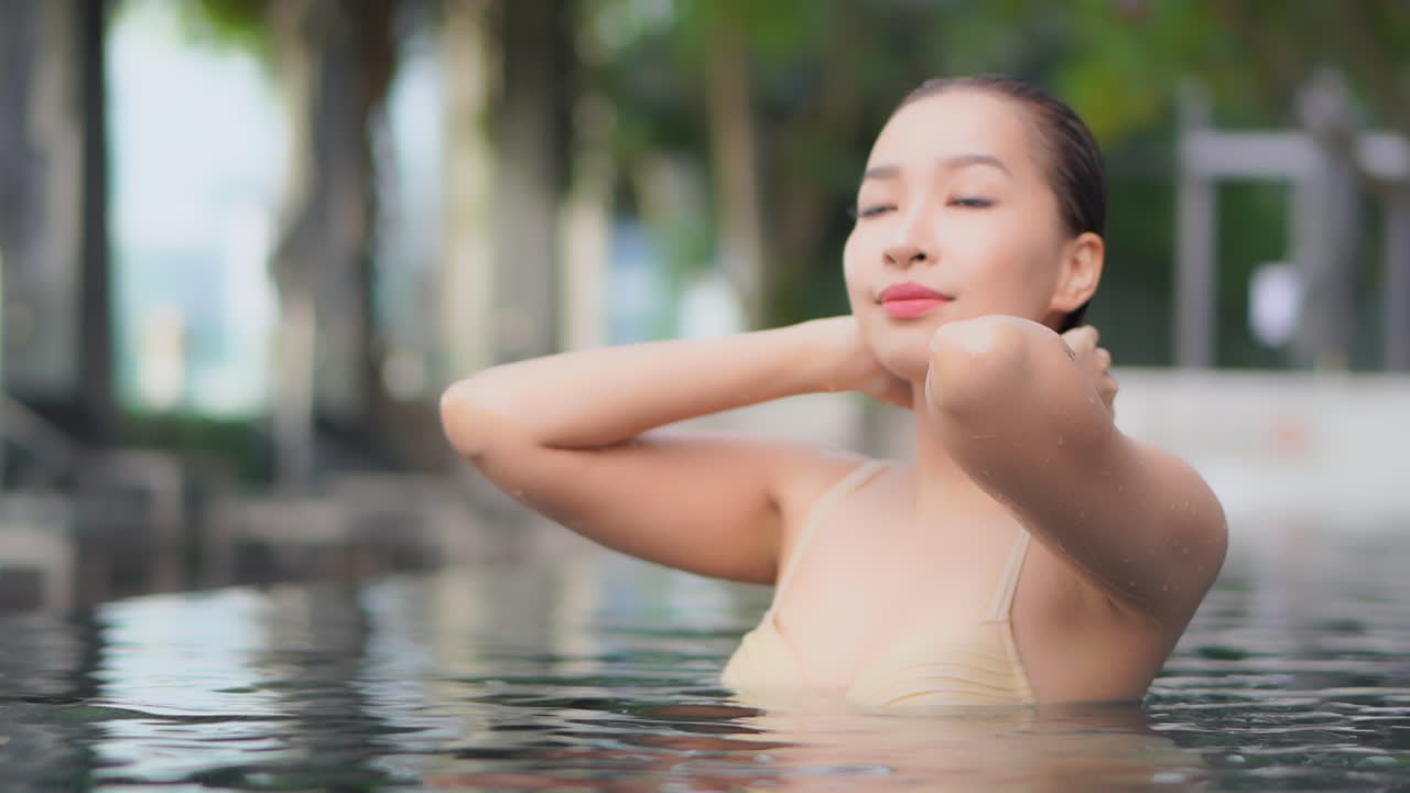 Pushing back her wet hair from her face a beautiful young woman's face reflects her inner peace