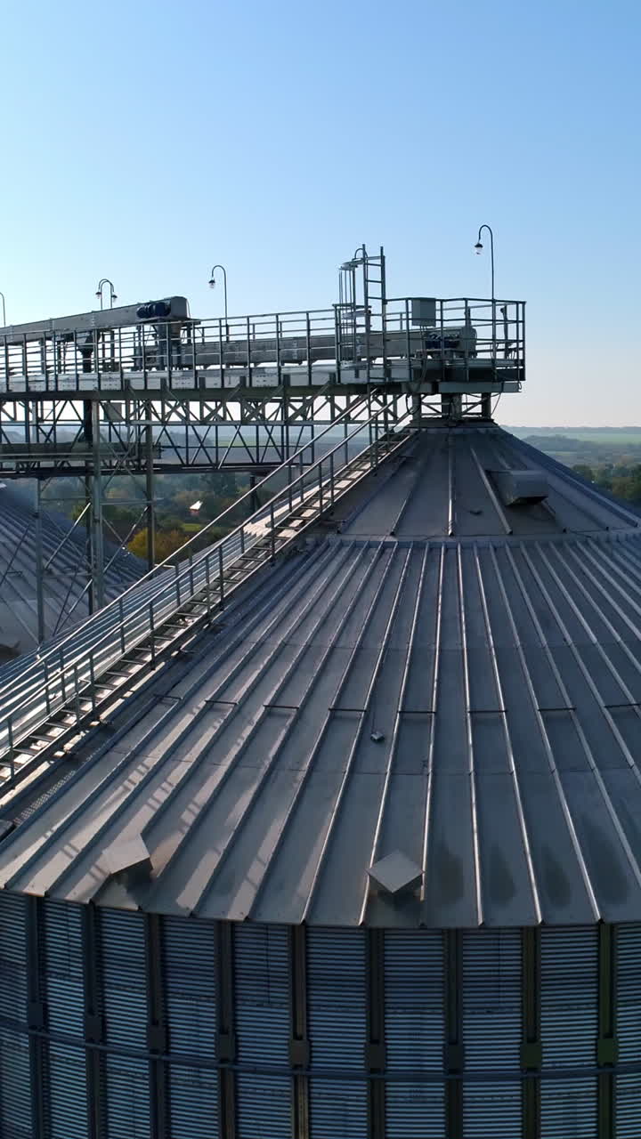 Metal elevator for crop. Silo for storing grain in the countryside. Exterior of large storage tanks for agricultural products. View from above. Vertical video