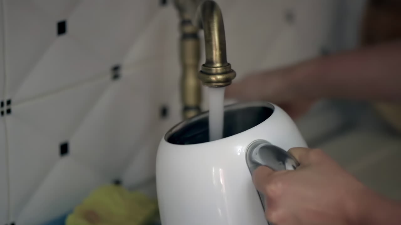 Woman rinsing the kettle with water in the sink