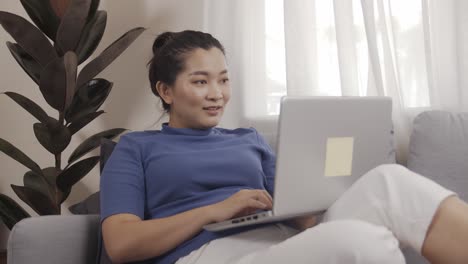 New-normal-businesswoman-work-from-home-by-laptop-sitting-on-the-sofa-happily