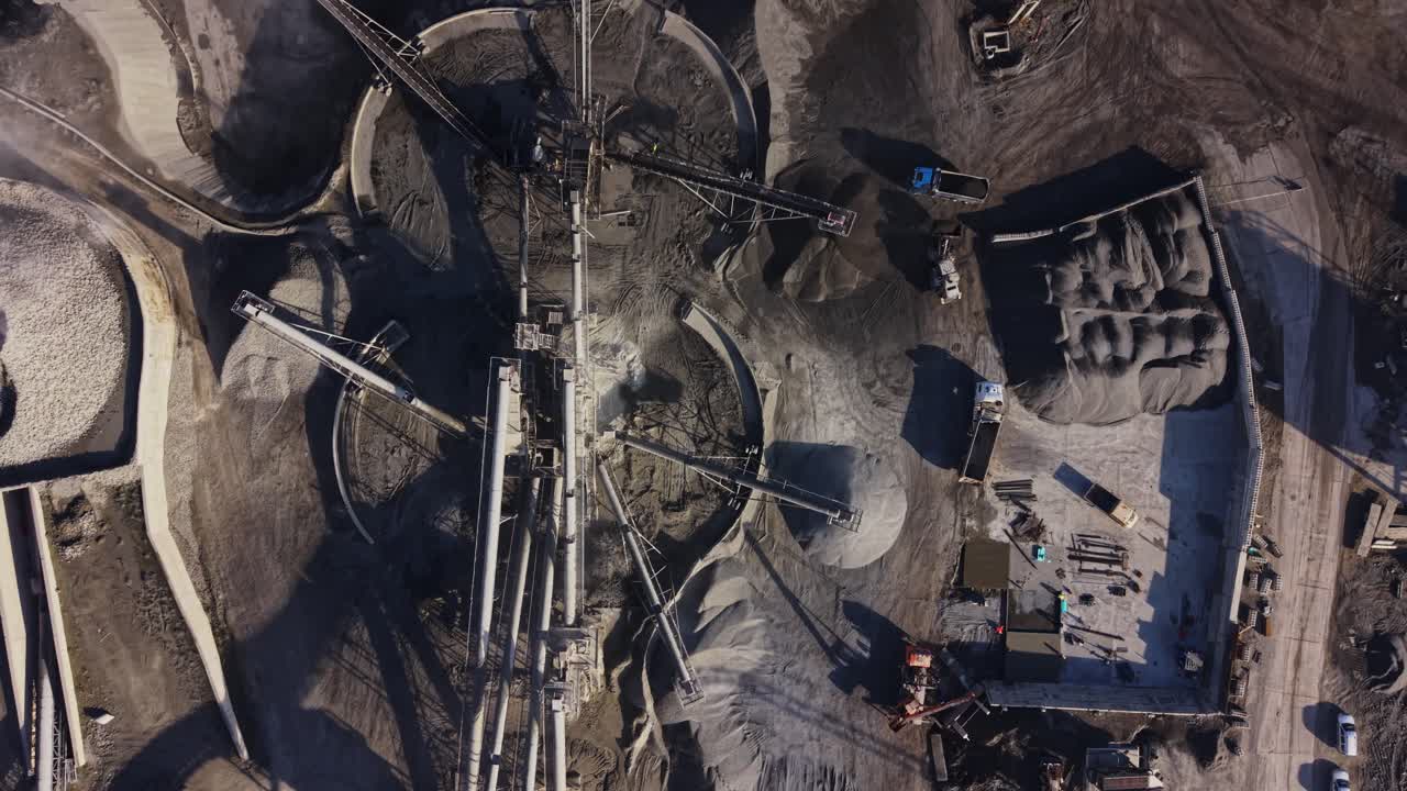 Workers operate machinery at a busy quarry site near a mine