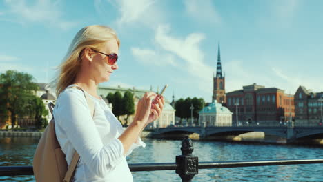 a young woman uses a smartphone against the background of the city line of stockholm sweden always i