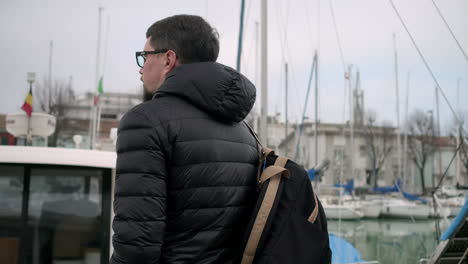 hombre con mochila en la marina en un día frío
