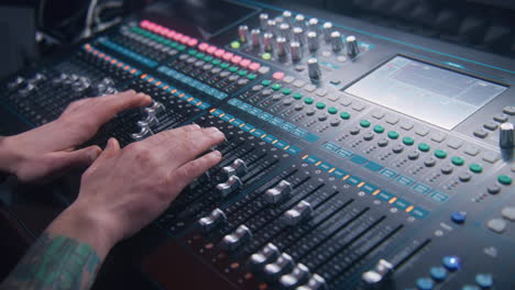 close up hands shot of sound engineer using mixing console, remote control for adjusting sound, audio mixer. musician creates music, makes remix for dj set. sound recording studio. music production.