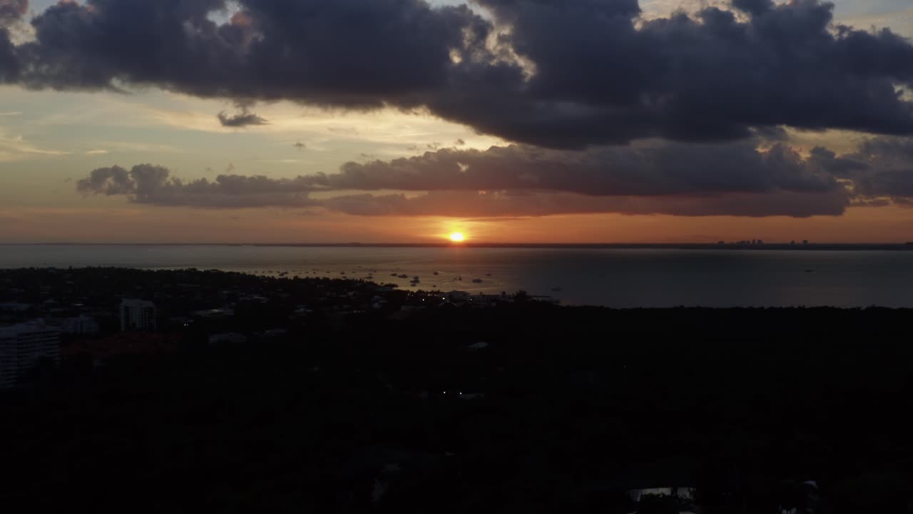 hermosa toma aérea de un impresionante atardecer naranja dorado del océano con vegetación tropical debajo de crandon park en key biscayne fuera de miami, florida en una cálida noche soleada de verano