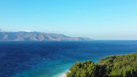 tropical-island-with-palm-trees-and-white-beach-with-turquoise-crystal-clear-seawater,-dramatic-sky-with-clouds