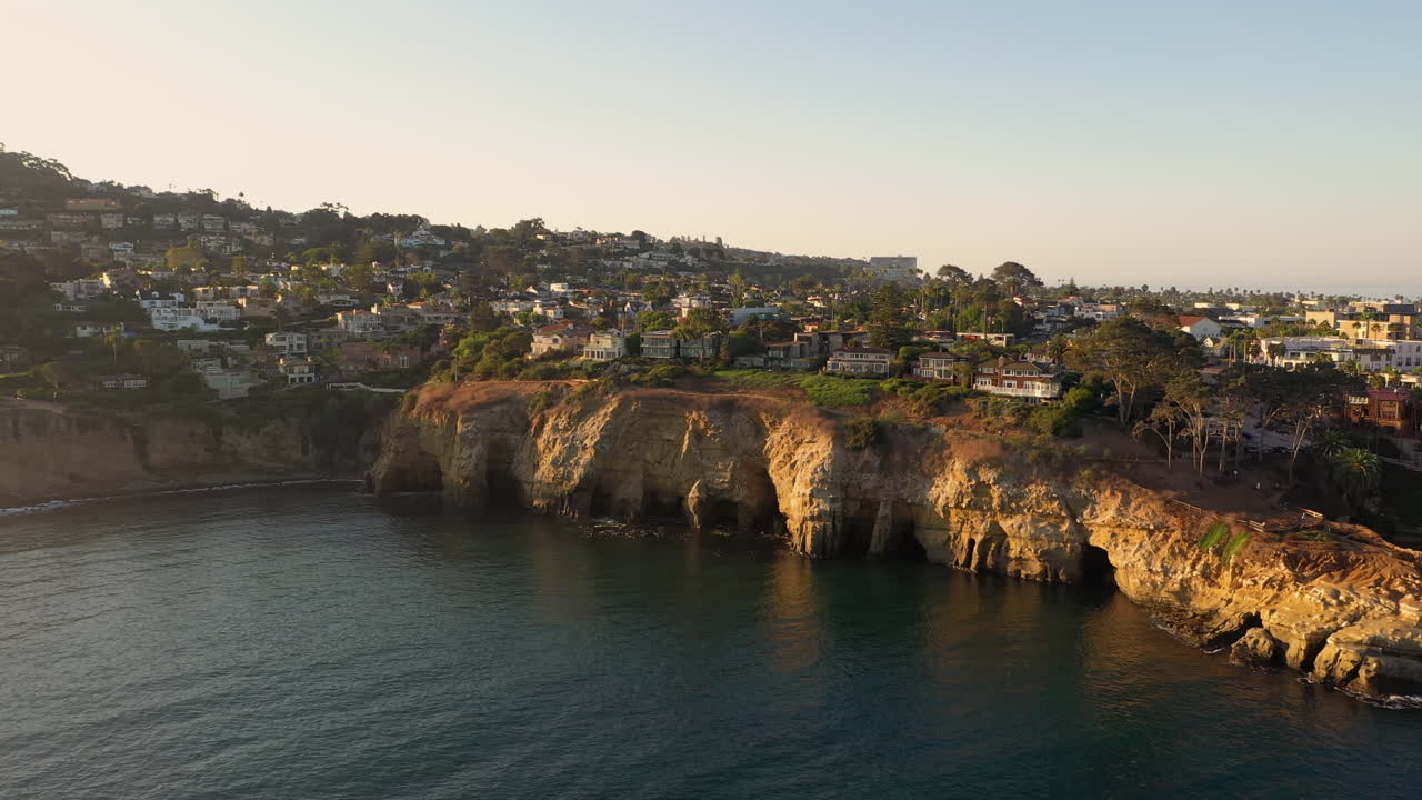 Toma de dron de cuevas costeras en La Jolla Cove en California con un hermoso atardecer - aéreo
