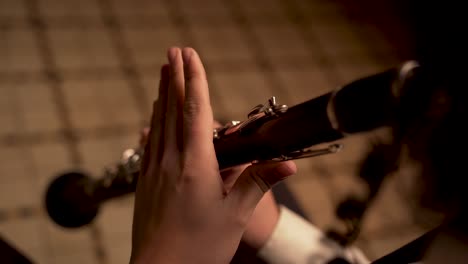reproductor de dedos en el clarinete, de cerca, en una habitación oscura