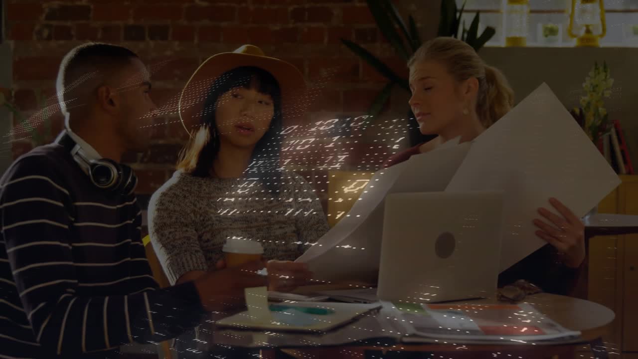 Man gesturing toward printed boards, colleagues designing in loft raising hologram grid over table