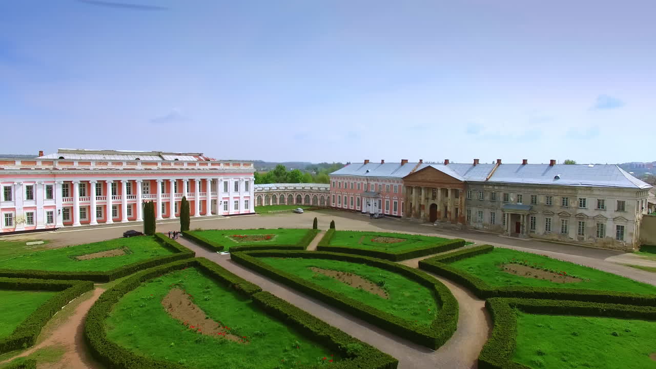 Flight above the green grass on the flower bed in front of the old palace. Museum ensemble in Ukrainian town.