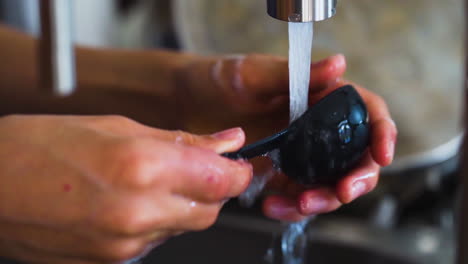 Woman-washing-a-spoon-in-the-kitchen-sink-in-slow-motion