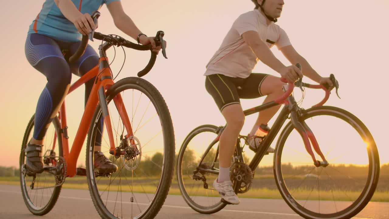 공허한 공간: 해가 지는 동안 자전거를 타는 스포츠 친구,  자전거 타는 남녀가 해안가를 따라 가고, 자연의 배경에서 스포츠, 한 무리의 사람들, 해가 지면 두 명의 도로 자전거 운전자.