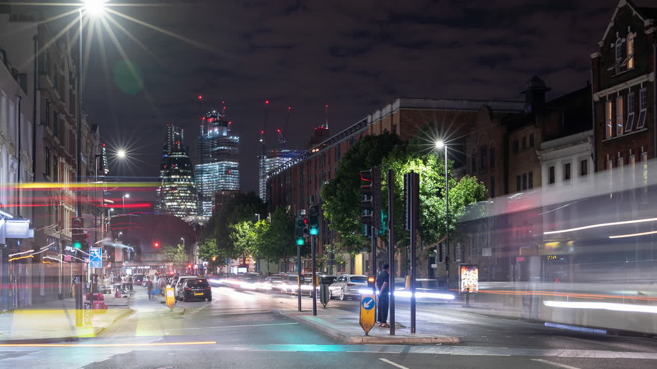 Night time lapse of a busy road in London, UK with cars and buses zooming past and skyscrapers skyline in the background
