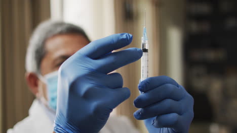 senior biracial male doctor preparing vaccination syringe