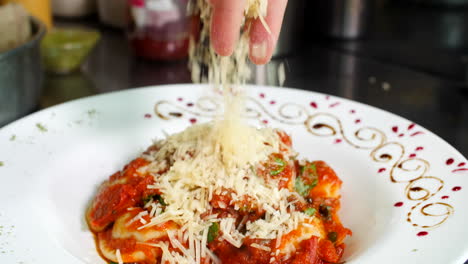 chef decorando ravioles con salsa de tomate en el restaurante agregando queso parmesano, primer plano, mediterráneo