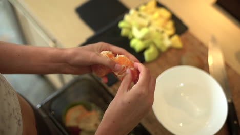 Close-Up-of-Female-Hands-Pulling-Citrus-Fruit-Segments-Apart