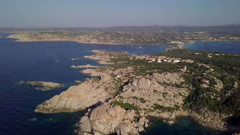 drone shot flying over a wild and rocky coastline towards a pristine bay in north sardinia