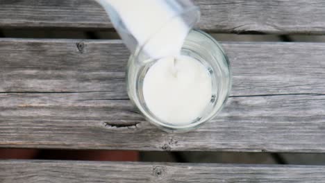 pouring milk into glass in the alps on a mountain, fresh from the cows location: south tyrol, italy