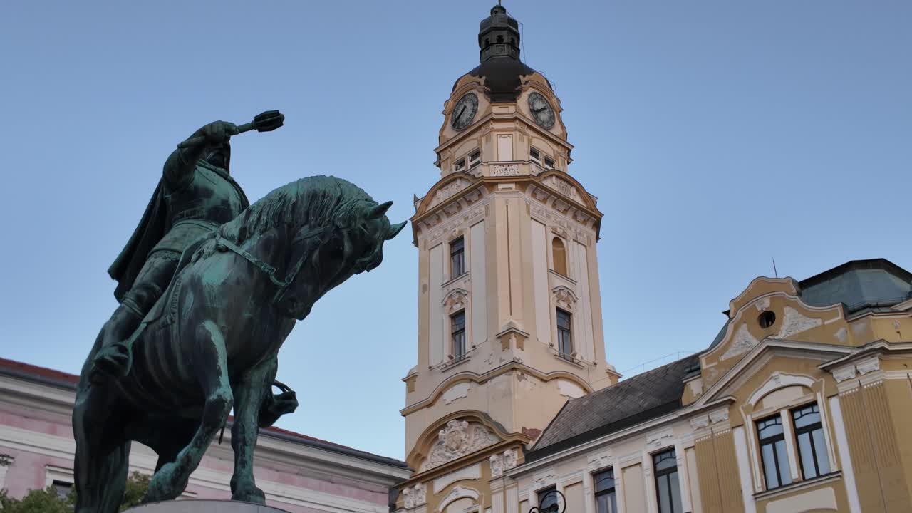 Historic and cultural scene in Pécs, Hungary, capturing the Hunyadi Statue before the ornate Town Hall