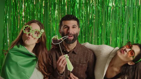 studio portrait shot of friends dressing up with irish novelties and props celebrating st patrick's day against green tinsel background 1