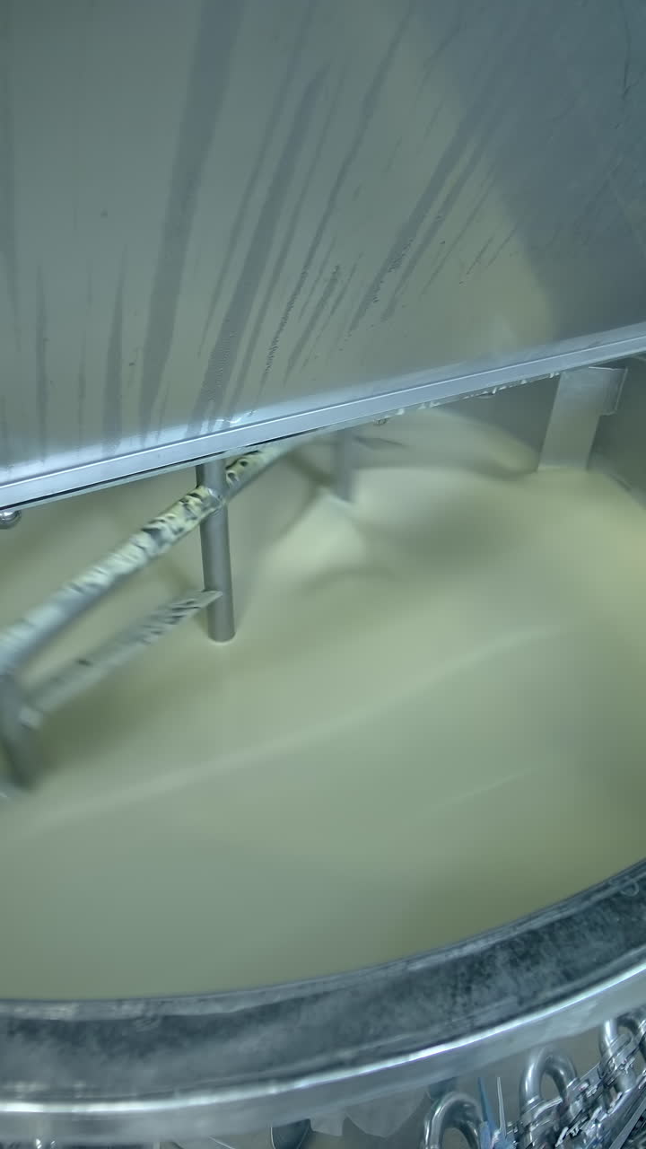 Industrial equipment for making butter. Modern container mixing butter at milk factory. Creamy dairy product in a tank Vertical video