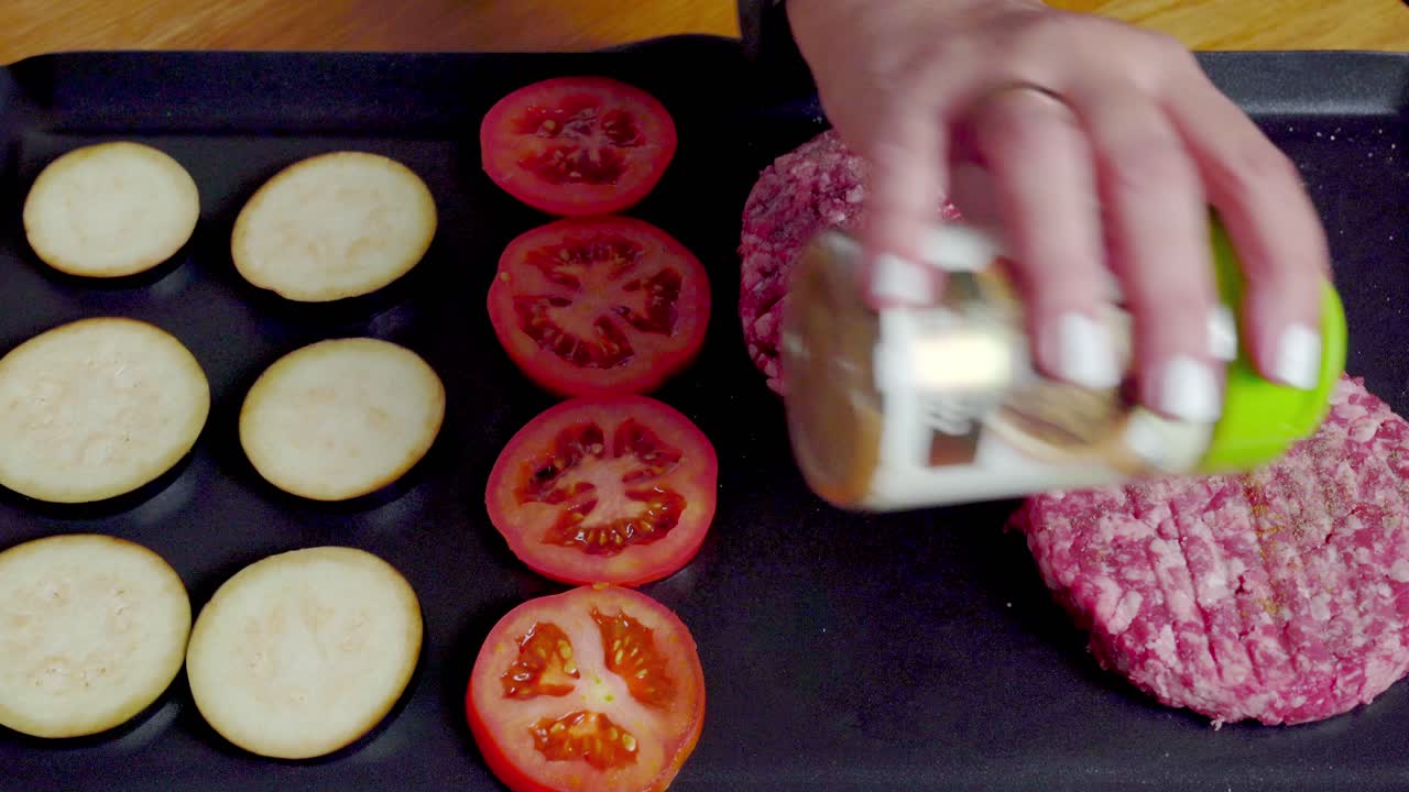 sazonando hamburguesas frescas y verduras en la parrilla de plancha