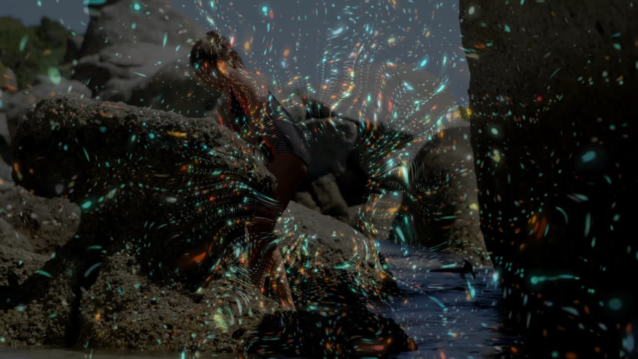 Sitting by water, person surrounded by colorful animation light patterns on rocks