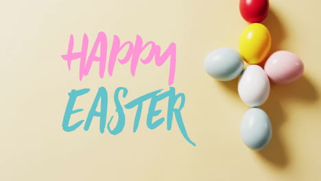 animation of happy easter text over colourful easter eggs on yellow background