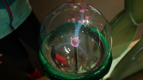 a girl puts fingers onto a plasma ball emitting electrical charge