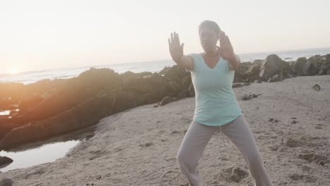 Ältere-Afroamerikanische-Frau-Macht-Yoga-Und-Stretching-Am-Strand,-Zeitlupe