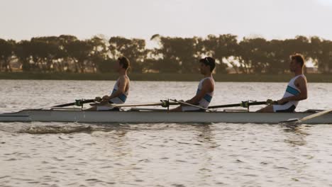 side view of male rower team rowing on the lake