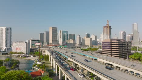 cars driving on elevated multilane highway. modern high rise apartment buildings in background. miami, usa