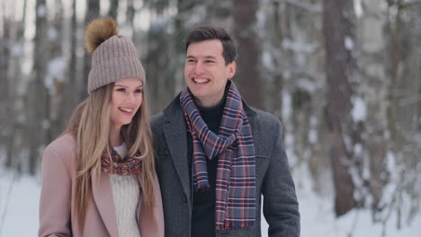 young married couple walks through the winter forest. a man and a woman look at each other laughing and smiling in slow motion.