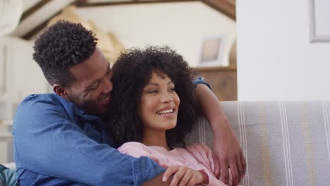 Happy-african-american-couple-embracing-together-in-living-room