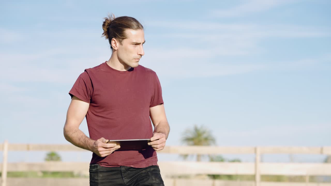 Young farmer inspecting land with a digital tablet