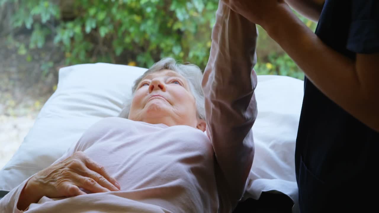 노인 여성 에게 어깨 치료 를 하는 물리 치료사 4k