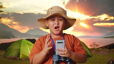 excited boy with smartphone and binoculars at sunset camping