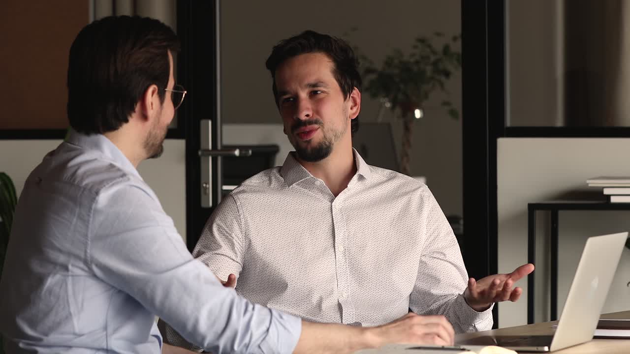 Happy two young mixed race businessmen discussing project.