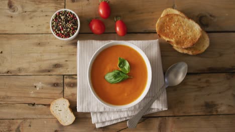 video of cream tomato soup in bowl on wooden table with tomato and bread